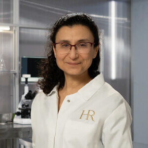 A scientist in a lab coat with 'HR' embroidered, standing confidently in a modern laboratory setting.