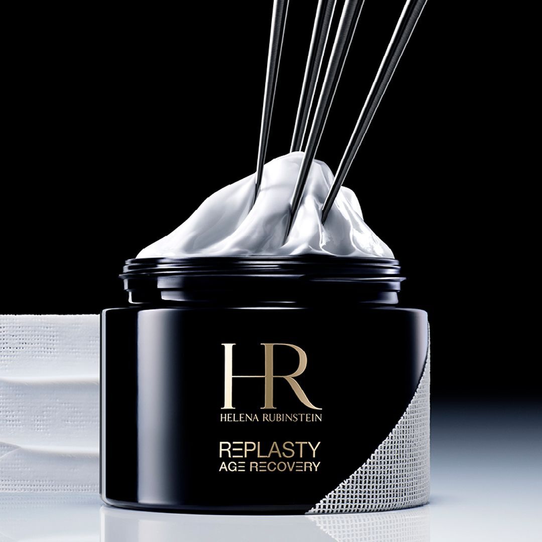 Helena Rubinstein Re-Plasty Age Recovery Banner: Eleganter schwarzer Cremetiegel, mittig platziert, mit goldenen Reflexionen und bernsteinfarbenen Flussigkeitselementen im Hintergrund. Dunkle und luxuriose Atmosphare.​