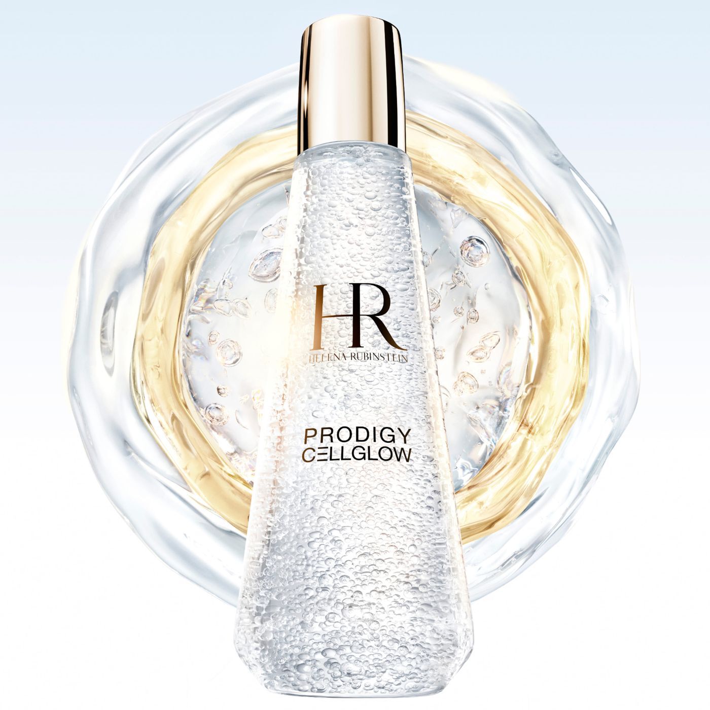 „Helena Rubinstein Prodigy Cellglow“ Serumflasche, gefullt mit Blaschen, im Zentrum von durchscheinenden und goldenen Flussigkeitsringen, die sich auf hellem Hintergrund ausbreiten.